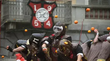 Sejumlah orang yang mengenakan helm melemparkan jeruk kepada warga sebagai bagian dari tradisi "perang jeruk" yang diselenggarakan selama Karnaval Ivrea di Turin, Italia (16/2). (AFP PHOTO/Olivier MORIN)