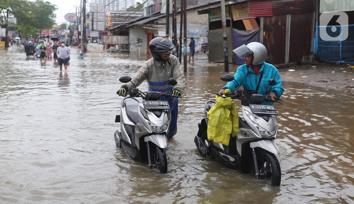 Pengendara motor mendorong kendaraannya melintasi genangan air ketika banjir merendam Jalan KH. Hasyim Ashari, Tangerang, Banten, Sabtu (16/7/2022). Hujan deras mengguyur sejak Jumat siang hingga Sabtu pagi. (Liputan6.com/Angga Yuniar)