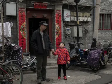 Seorang kakek bersama cucunya berbincang di halaman di luar rumah mereka di daerah hutong di Beijing (26/2). Hutong adalah jenis jalan sempit atau gang yang biasanya dikaitkan dengan kota-kota Cina utara, terutama Beijing.  (AFP Photo/Nicolas Asfouri)