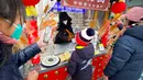 Seorang anak mengambil permen berbentuk pistol dari stan yang disiapkan untuk pekan liburan Tahun Baru Imlek di sebuah taman umum di Beijing, China, Kamis (26/1/2023). (AP Photo/Mark Schiefelbein)