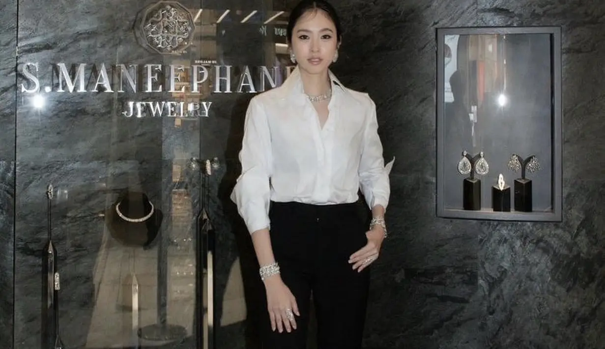 Kemeja tersebut dipadukan dengan celana hitam bahannya. Meski pakaian nampak simple, namun ia terlihat mewah mengenakan kalung, gelang, dan anting silvernya. Credit: @poydtreechada