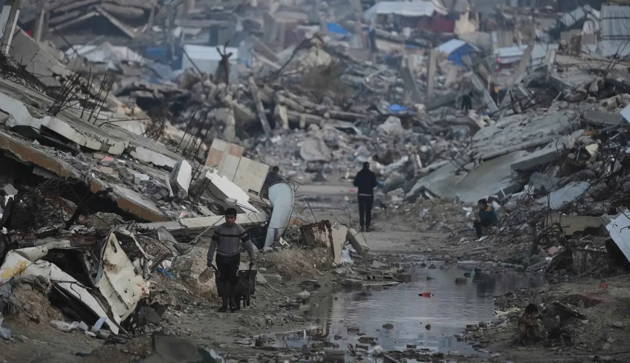 Menurut Direktur Operasi Komite Internasional Palang Merah (ICRC), Yasmine Praz Dessimoz, pembukaan kembali perlintasan di perbatasan Rafah sangat penting untuk menyediakan bantuan kemanusiaan dalam jumlah yang cukup ke Jalur Gaza. Tampak dalam foto, warga Palestina berjalan di tengah bangunan yang hancur akibat serangan udara dan darat Israel di Kota Gaza, Selasa 6 Januari 2026. (AP Photo/Jehad Alshrafi)