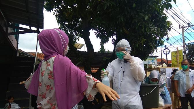 Petugas KPPS di Kabupaten Bandung kenakan Baju Hazmat sambut calon pemilih di TPS. (Liputan6.com/Dikdik Ripaldi)