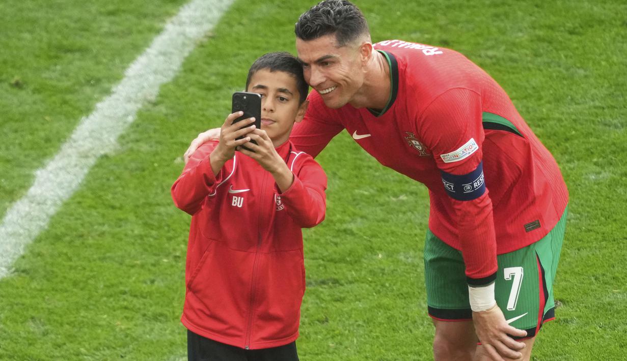 <p>Seorang fans cilik mengajak kapten Timnas Portugal, Cristiano Ronaldo untuk berselfie di sela laga matchday kedua Grup F Euro 2024 antara Timnas Turki menghadapi Timnas Portugal Westfalenstadion, Dortmund, Jerman, Sabtu (22/6/2024). (AP Photo/Michael Probst)</p>