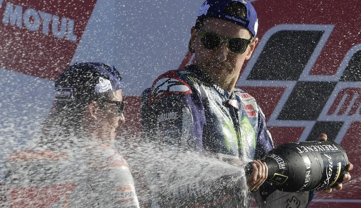 Jorge Lorenzo menyemprotkan sampanye ke arah Marc Marquez di atas podium juara MotoGP Valencia di Sirkuit Ricardo Tormo, Minggu (13/11/2016). (AFP/Javier Soriano)