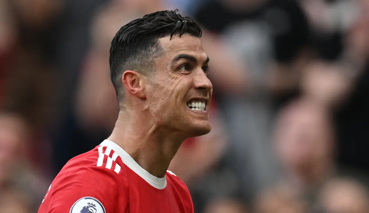 Penyerang Man United, Cristiano Ronaldo unjuk gigi dihadapan pendukung Setan Merah usai dirinya mencetak hat-trick saat melawan Norwich City di pekan ke-32 Liga Inggris 2021/2022. (AFP/Paul Ellis)