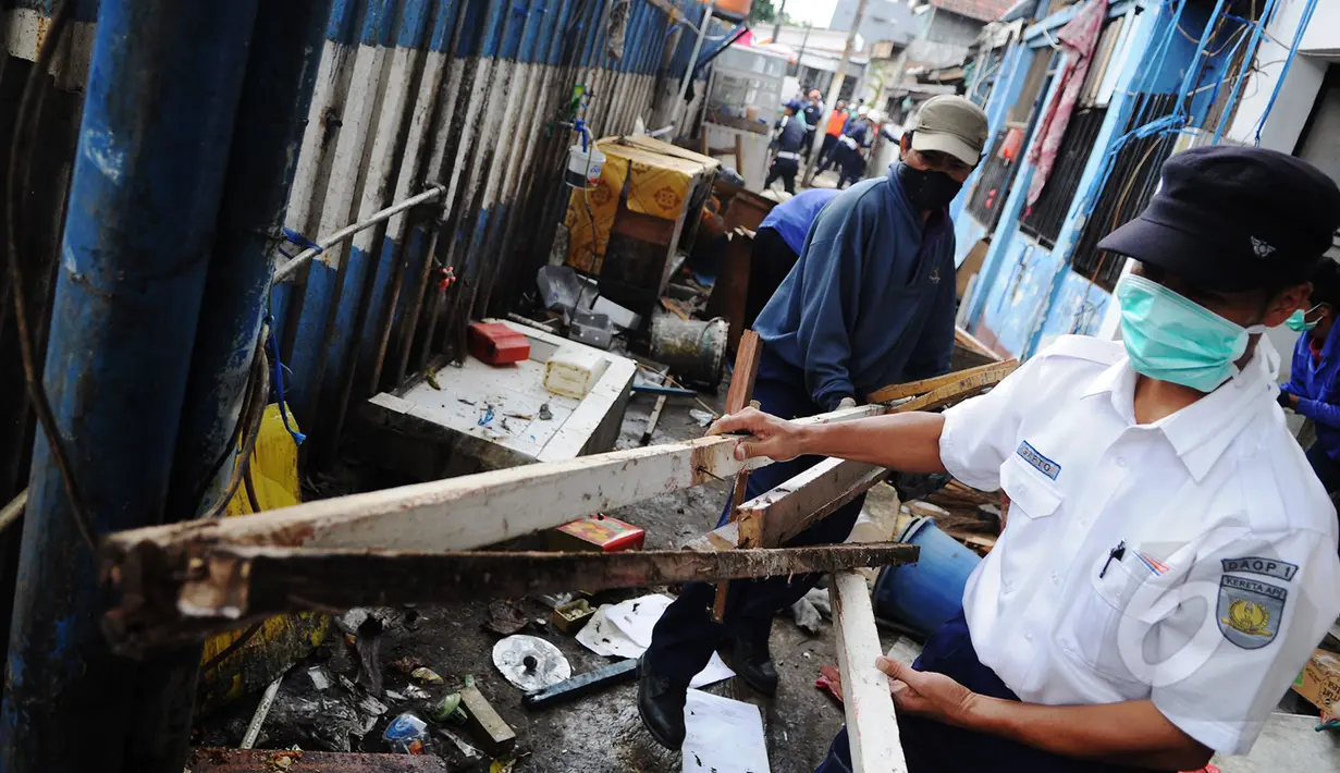 Petugas PT.KAI mengangkat puing di kawasan Stasiun Kemayoran, Jakarta, Senin (9/3/2015).  Pembongkaran sembilan rumah warga yang masih berdiri di kawasan Stasiun kemayoran dilakukan oleh tim gabungan PT KAI. (Liputan6.com/Faizal Fanani)