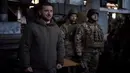 Presiden Ukraina Volodymyr Zelenskyy (kiri) berbicara kepada tentara di lokasi pertempuran terberat melawan Rusia di Bakhmut, Ukraina, 20 Desember 2022. Mengambil Bakhmut akan merusak jalur pasokan Ukraina dan membuka rute bagi pasukan Rusia untuk maju terus menuju Kramatorsk dan Sloviansk, benteng utama Ukraina di wilayah tersebut. (Ukrainian Presidential Press Office via AP)