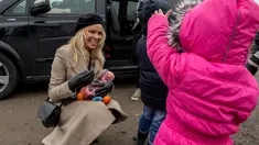 Aktris asal Kanada, Pamela Anderson memberikan buah-buahan kepada seorang anak di pengungsian Grande-Synthe, Prancis (25/1). Dalam kunjungannya, Pamela menyumbangkan buku anak-anak, makanan serta perlengkapan lainnya. (AFP/Philippe Huguen)