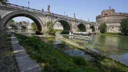 Sebuah feri turis berlayar ketika tanaman muncul di dasar sungai Tiber dengan daun seperti rawa mengambang di tepinya, di Roma, Italia, Senin, 4 Juli 2022. Sungai utama Roma telah mencapai tingkat air terendah dalam beberapa tahun setelah berhari-hari kekurangan hujan dan panas yang berlebihan. (AP Photo/Andrew Medichini)