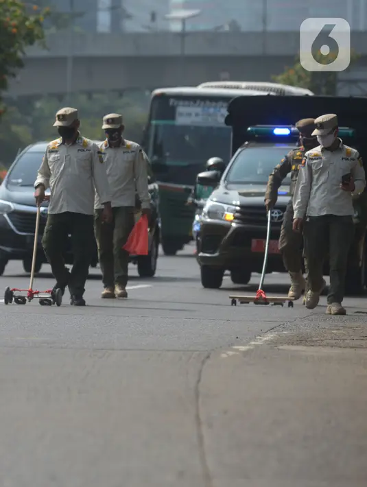 Petugas Satpol PP melakukan penyisiran Jalan Gatot Subroto dari ranjau paku di Jakarta, Sabtu (16/10/2021). Kegiatan penertiban ranjau paku ini untuk memberikan rasa aman dan nyaman bagi pengendara saat melintas di jalanan. (merdeka.com/Imam Buhori)