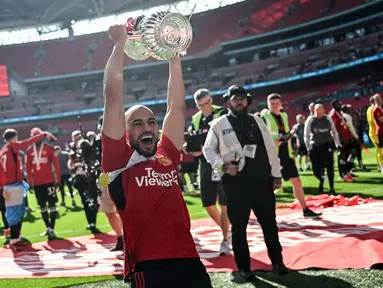 Pemain Manchester United, Sofyan Amrabat mengangkat trofi saat merayakan gelar juara Piala FA 2023/2024 di Stadion Wembley, London, Sabtu (26/05/2024). MU menang dengan skor 2-1 atas Manchester City di partai final. (AFP/Justin Tallis)