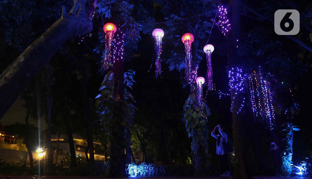 Warga saat memotret Jakarta Lights Festival di Taman Sumenep, Jakarta, Jumat (23/12/2022). Pemprov DKI Jakarta menggelar acara Jakarta Lights Festival sebagai rangkaian perayaan Natal dan Tahun Baru (Nataru) 2023. (Liputan6.com/Herman Zakharia)