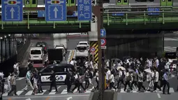 Orang-orang berjalan di atas penyeberangan pejalan kaki di bawah terik matahari di Tokyo, Senin (30/5/2022). Cuaca panas pada hari Senin telah ditetapkan dengan suhu naik lebih dari 27 derajat Celcius (80,6 derajat Fahrenheit) di Tokyo, menurut Badan Meteorologi Jepang. (AP Photo/Eugene Hoshiko)