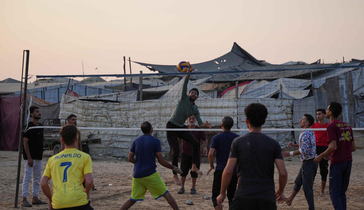 Anak-anak muda Palestina bermain voli di kamp tenda pengungsian di Zawayda, Jalur Gaza tengah, Selasa 4 November 2025. Sejumlah komunitas internasional terus memantau perkembangan gencatan senjata dengan keprihatinan mendalam. (AP Photo/Abdel Kareem Hana)