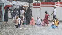 Anak-anak saat bermain di tengah banjir yang merendam Jalan Abdullah Syafei, Tebet, Jakarta, Kamis (18/2/2021). Menurut warga setempat, banjir ini merupakan yang pertama kali terjadi yang diduga disebabkan adanya proyek revitalisasi kolong flyover. (merdeka.com/Iqbal S Nugroho)