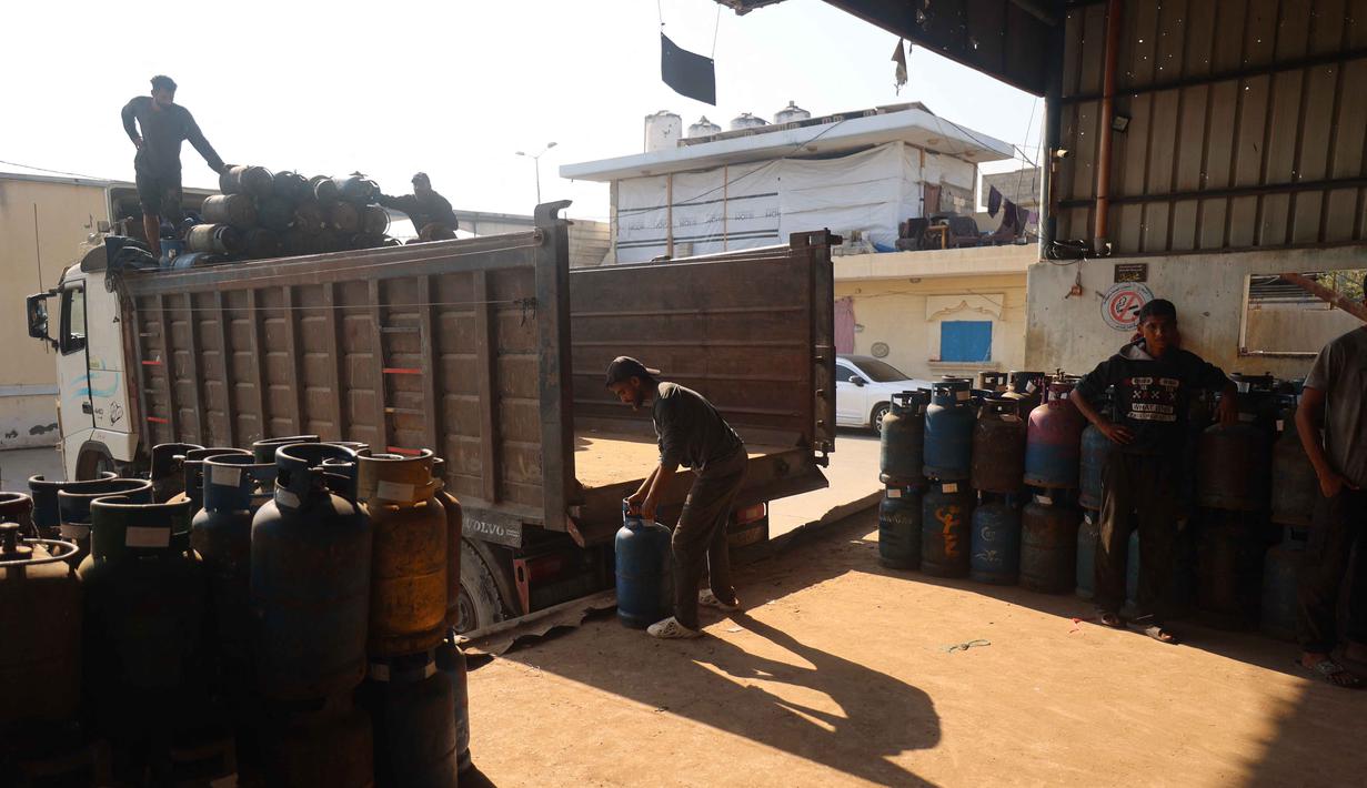Kembalinya pasokan bahan bakar gas ke Gaza—meski dalam jumlah terbatas—memberikan secercah harapan bagi keluarga yang selama ini hidup dalam kegelapan dan kelaparan. Tampak dalam foto, pekerja Palestina memuat tabung gas, untuk pertama kalinya dalam setahun, di stasiun pengisian resmi di kamp pengungsi Nuseirat, di bagian tengah Jalur Gaza, pada 10 November 2025. (Eyad Baba/AFP)