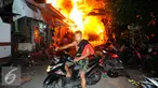 Seorang warga menyelamatkan diri dari kebakaran yang terjadi di belakang Senayan City, Jakarta, Minggu (3/7) dini hari. Sejumlah rumah semi permanen terbakar 38 mobil pemadam kebakaran dikerahkan. (Liputan6.com/Helmi Afandi)