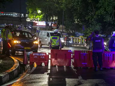 Polisi berjaga saat penyekatan jalan di kawasan Pasar Baru, Jakarta, Kamis (31/12/2020). Polda Metro Jaya menutup sejumlah ruas jalan selama Car Free Night dan Crowd Free Night pada malam Tahun Baru 2021 untuk mencegah penyebaran COVID-19. (Liputan6.com/Faizal Fanani)