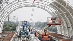 Pekerja menyelesaikan proyek pembangunan Light Rail Transit (LRT) Jabodebek di Stasiun LRT TMII, Jakarta, Senin (14/1). Stasiun LRT TMII dibangun dua lantai yang terdiri dari komersial dan pembelian tiket. (Liputan6.com/Faizal Fanani)