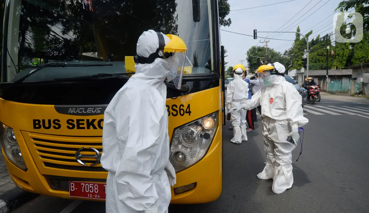 Petugas Dishub memakai baju APD akan menjemput korban yang diduga terjangkit Covid-19 menggunakan bus sekolah di Puskesmas Kebayuran Lama, Jakarta, Senin (6/7/2020). Bus sekolah tersebut selama liburan dibantukan untuk mengangkut pasien Covid-19 ke Wisma Atlet Kemayoran. (merdeka.com/Dwi Narwoko)