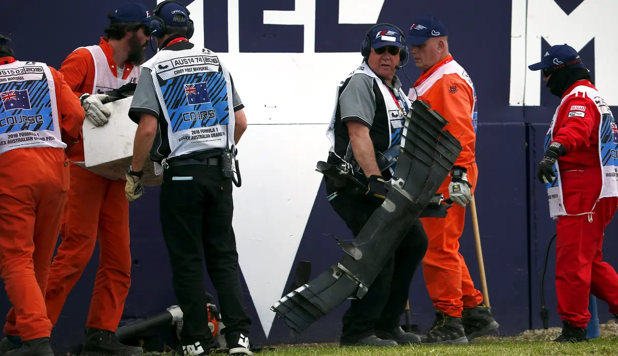 Para marshal mengumpulkan puing dari mobil balap yang hancur akibat kecelakaan saat pertarungan di lap 17 F1 Grand Prix Australia di Melbourne, Minggu (20/3). Balap Grand Prix Australia sempat dihentikan akibat kecelakaan tersebut. (REUTERS/Joe Castro)
