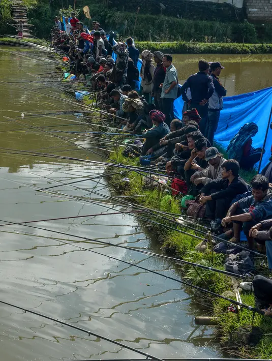 Para peserta pria berkonsentrasi dengan kailnya pada kompetisi memancing di sebuah kolam dekat desa Weilei di Negara Bagian Meghalaya, timur laut India, Sabtu (21/9/2019). Ratusan peserta berpartisipasi dalam kompetisi yang memperebutkan sejumlah hadia tersebut. (DIPTENDU DUTTA / AFP)