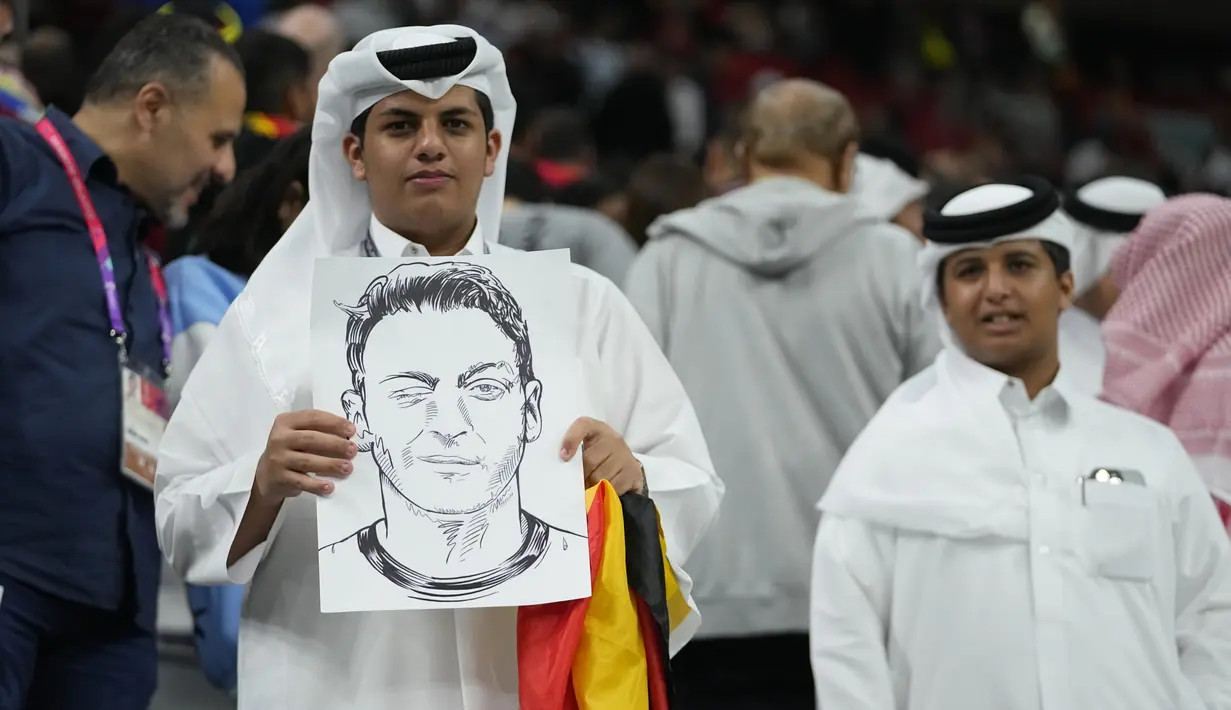 Seorang penonton memegang sketsa mantan pesepakbola Jerman Mesut Ozil pada akhir pertandingan Spanyol vs Jerman saat laga Grup E Piala Dunia 2022  di Stadion Al Bayt, Kota Al Khor pada Senin (28/11/2022) dini hari WIB. Perlu diketahui bahwa Mesut Ozil mundur dari karier timnasnya tidak lama setelah hasil mengecewakan Jerman di babak penyisihan grup di Piala Dunia 2018 Rusia. (AP Photo/Julio Cortez)