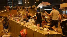Demonstran membersihkan sampah setelah aksi menolak RUU ekstradisi di Hong Kong (12/6/2019). Aksi tersebut berujung bentrok antara polisi dan warga dimana puluhan ribu orang memblokir jalan-jalan di kota tersebut. (AFP Photo/Hector Retamal)