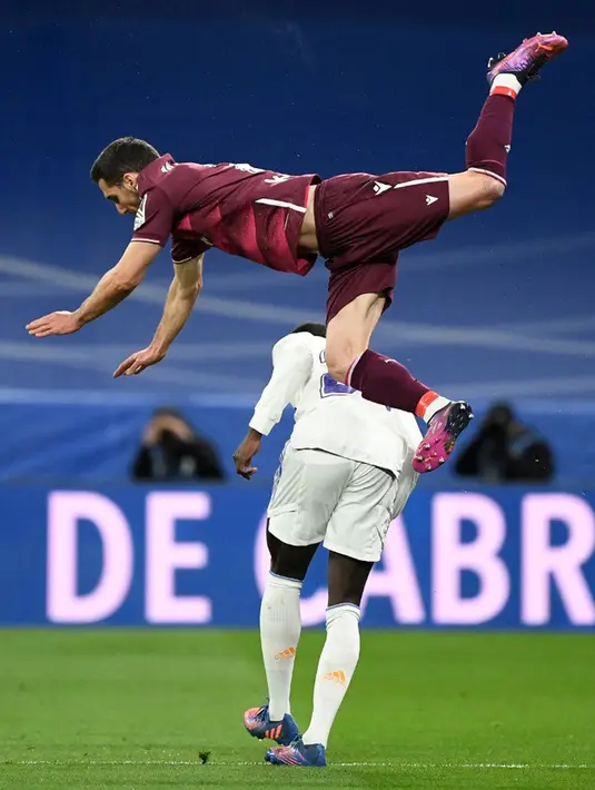 Pemain Real Sociedad Joseba Zaldua (atas) melompati pemain Real Madrid Ferland Mendy pada pertandingan sepak bola Liga Spanyol di Stadion Santiago Bernabeu, Madrid, Spanyol, 5 Maret 2022. Real Madrid menang 4-1. (PIERRE-PHILIPPE MARCOU/AFP)