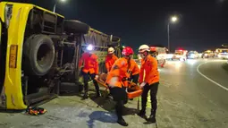 Bus diduga melaju dengan kecepatan tinggi sebelum menabrak pembatas jalan di tikungan jalur penghubung dan terguling hingga atap kabin ringsek. Tampak dalam foto, personel dari Badan Nasional Pencarian dan Pertolongan (Basarnas) Semarang melakukan evakuasi korban kecelakaan bus di Exit Tol Krapyak Kota Semarang, Jawa Tengah, Senin (22/12/2025) dini hari. (Foto: Basarnas Semarang)