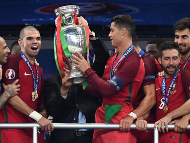 Pemain Timnas Portugal, Cristiano Ronaldo dan Pepe menerima trofi Piala Euro setelah mengalahkan Prancis di final Piala Euro 2016 yang berlangsung di Stade de France, Paris, (10/7/2016). (AFP/Franck Fife)