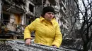 Seorang wanita membersihkan puing-puing di bangunan tempat tinggal yang rusak setelah peluru militer Rusia menghantam di Koshytsa Street, Kiev, Ukraina (25/2/2022). Serangan udara pada Kamis (23/2) dengan cepat merenggut puluhan nyawa dan membuat sedikitnya 100.000 orang mengungsi. (AFP/Daniel Leal)