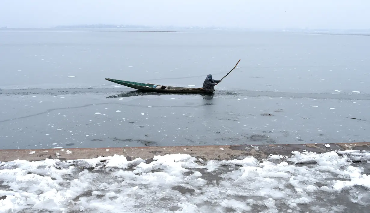 Seorang nelayan beraktivitas di danau Dal yang beku di Srinagar, Kashmir yang dikuasai India (7/1). Musim salju telah mengakibatkan gangguan lalu lintas udara dan lalu lintas jalan antara Srinagar dan Jammu. (AFP Photo/Tauseef Mustafa)