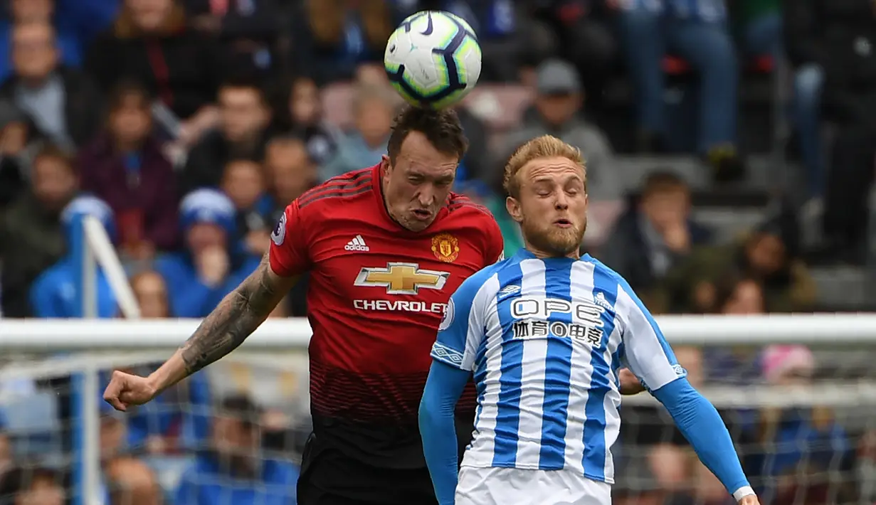 Bek Manchester United, Phil Jones, duel udara dengan pemain Huddersfield Town, Alex Pritchard, pada laga Premier League di Stadion John Smith, Minggu (5/5). Kedua tim bermain imbang 1-1. (AFP/Paul Ellis)