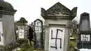 Seorang wanita berjalan di sebuah pemakaman Yahudi di Strasbourg, Prancis (17/12).  Sebanyak 37 batu nisan dirusak dengan lambang swastika Nazi yang dicat semprot dan grafiti lainnya. (AFP Photo/Sebastien Bozon)