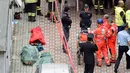 Petugas berdiri di dekat tiga jasad korban robohnya sebuah rumah susun akibat ledakan di Milan, Italia, Minggu (12/6) waktu setempat. Ledakan itu meruntuhkan sebagian gedung tersebut. (REUTERS/Flavio Lo Scalzo)