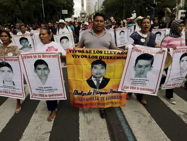 Sejumlah kerabat memegang poster bergambar 43 mahasiswa yang hilang dalam protes di Meksiko, (26/8/2015). Para mahasiswa menghilang sejak 26 September 2014 di kota barat daya Iguala. (REUTERS/Henry Romero)