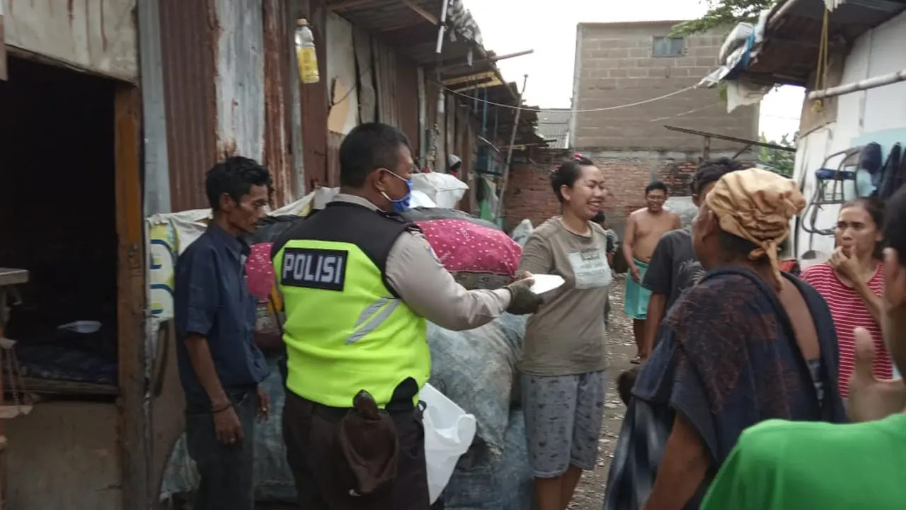 Polisi membagikan paket nasi pada warga terdampak covid-19. Foto: Liputan6.com/Bam Sinulingga