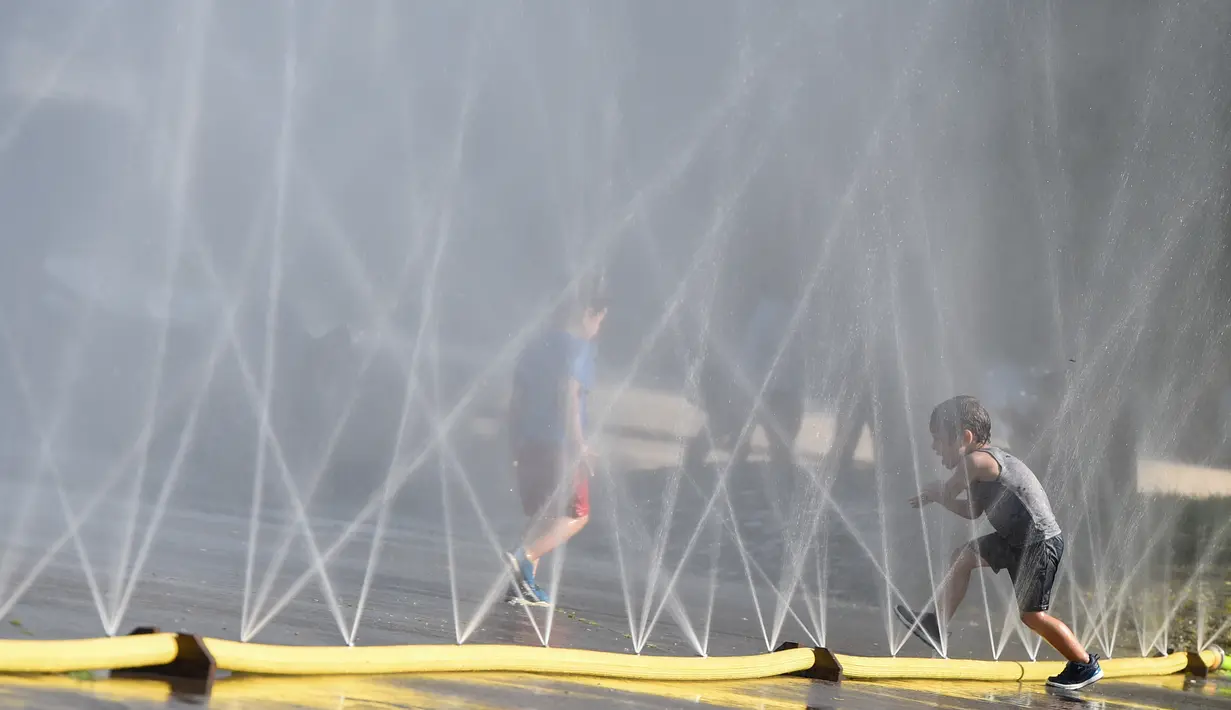 Anak-anak menyejukkan diri di dekat semprotan air di Schwarzenbergplatz di Wina, Austria (28/7/2020). Suhu tertinggi di Wina mencapai angka 37,2 derajat Celsius pada Selasa (28/7). (Xinhua/Guo Chen)