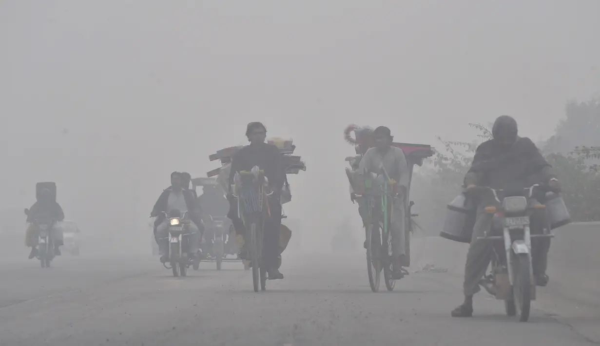 Pengendara motor melintas saat kabut asap tebal di Lahore (21/11/2019). Dokter juga mengatakan orang yang merasakan dampak kabut asap harus minum banyak air, bilas mata mereka setidaknya sekali dalam satu jam, dan memakai masker wajah jika mereka harus bepergian ke luar. (AFP Photo/Arif Ali)