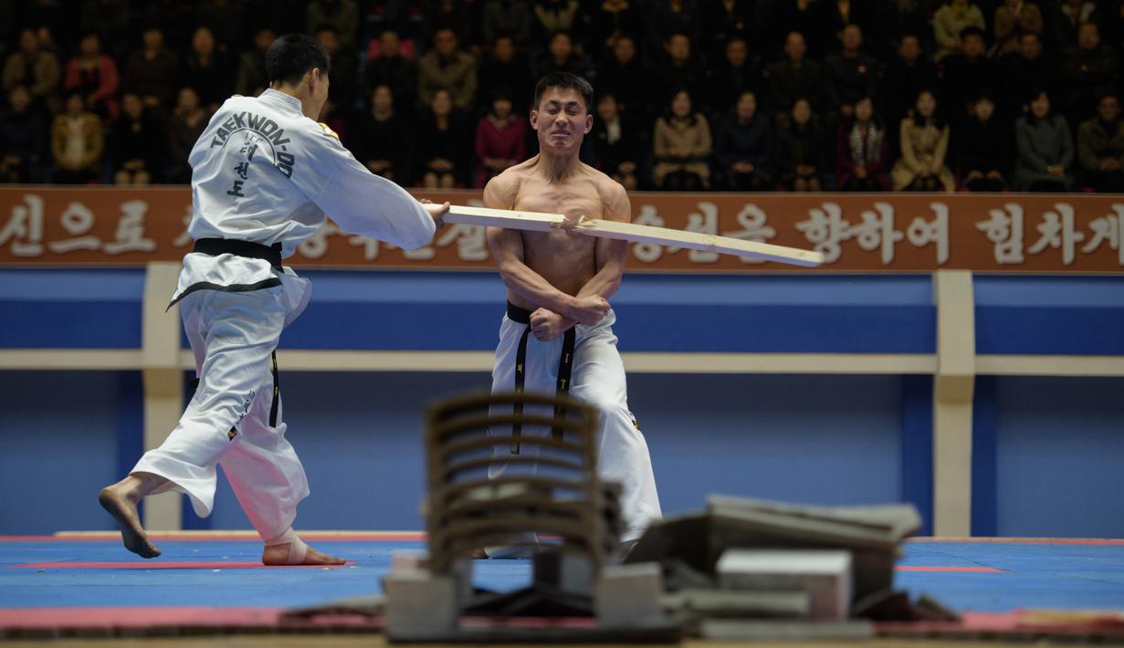 Seorang peserta saat dipukul dengan kayu selama demonstrasi taekwondo sebagai bagian dari Kejuaraan Seni Bela Diri Nasional tahunan Mangyongdae di 'Taekwon-Do Hall' di Pyongyang, Korea Utara (9/11). (AFP Photo/Kim Won Jin)