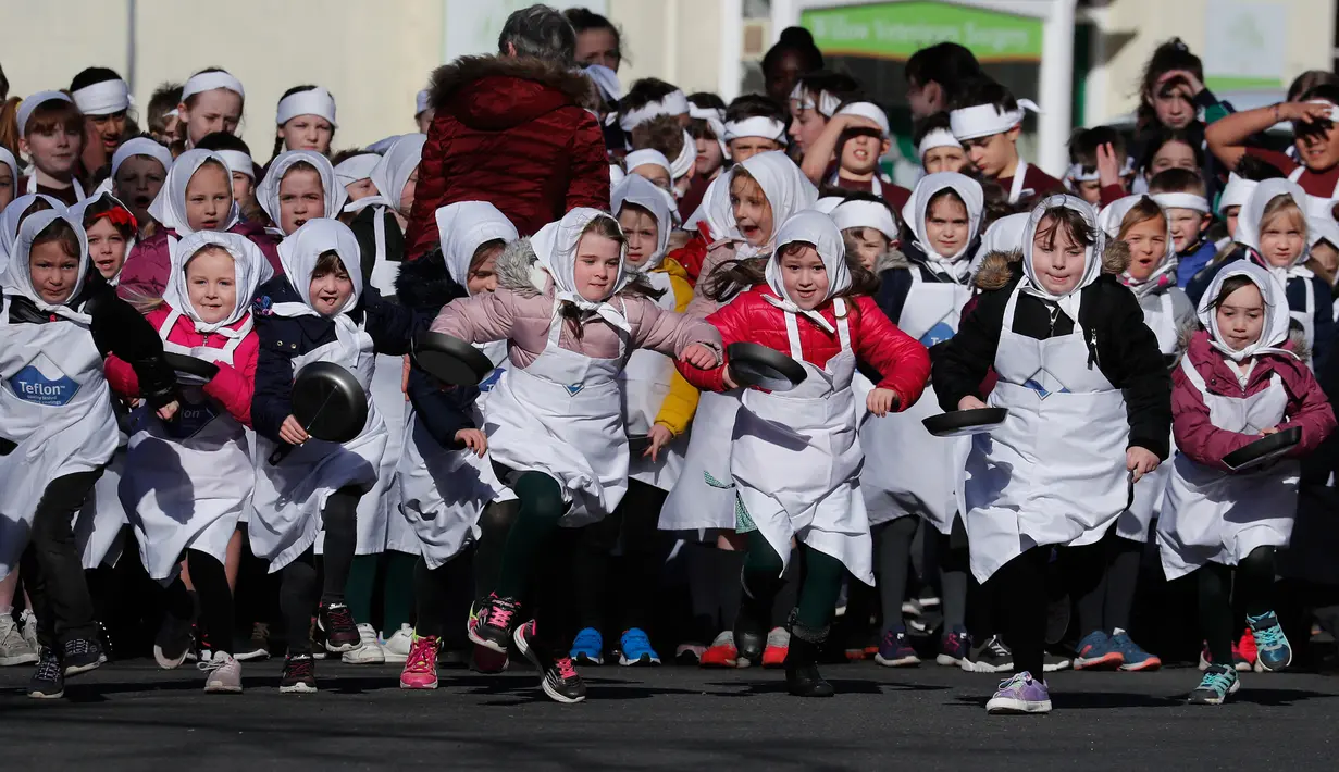 Anak-anak berpartisipasi mengikuti lomba lari dengan membawa pancake dalam lomba tahunan Pancake Trans-Atlantic, di kota Olney, Buckinghamshire, Inggris, Selasa (5/3). Lomba pada Hari Pancake ini diadakan satu hari menjelang Rabu Abu. (AP/Frank Augstein)