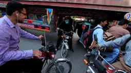 Sejumlah pengendara motor melewati kolong sebuah truk kontainer di Rawalpindi, Pakistan (28/10). Tanpa rasa takut para pengendara motor tersebut melintasi kolong truk yang membawa peti kemas. (Reuters/Faisal Mahmood)