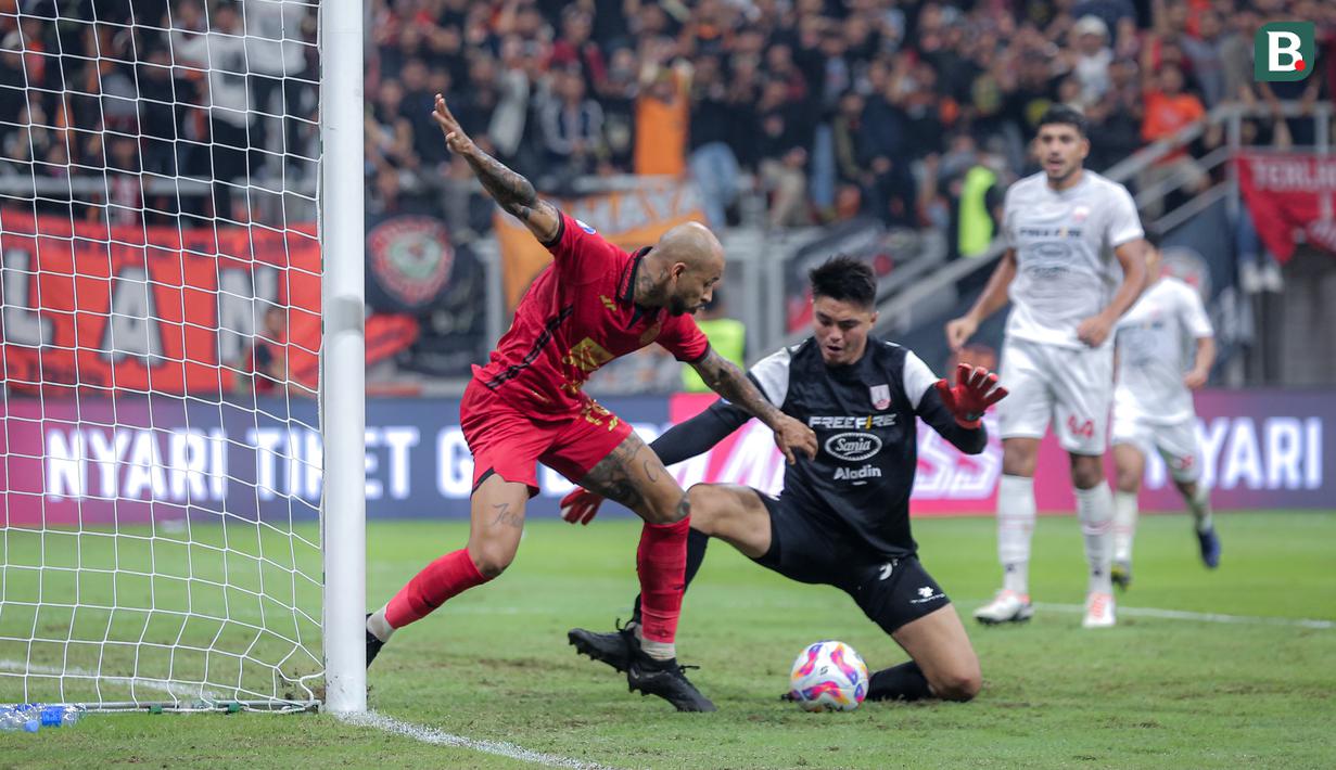 Pemain Persija Jakarta, Gustavo Almeida (kiri) berebut bola dengan kiper Persis Solo, Gianluca Claudio pada laga lanjutan BRI Liga 1 2024/2025 di Jakarta International Stadium (JIS), Jakarta Utara, Sabtu (24/08/2024). (Bola.com/Bagaskara Lazuardi)