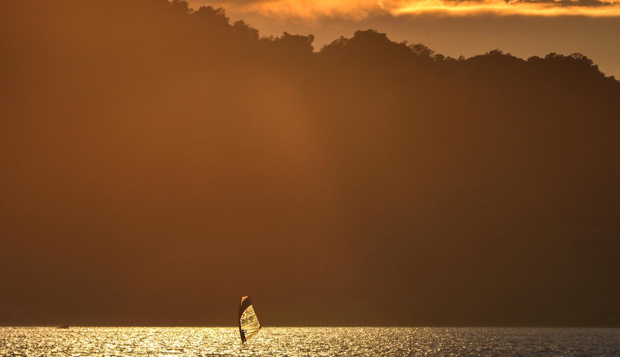 Seorang pria bermain selancar angin saat matahari terbenam di sebuah pantai di Banda Aceh (7/4). Kota Banda Aceh merupakan salah satu kota yang berada di Aceh dan menjadi ibukota Provinsi Aceh, Indonesia. (AFP Photo/Chaideer Mahyuddin)