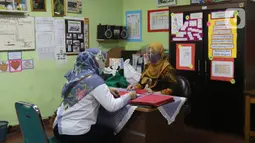 Guru membagikan laporan hasil belajar (rapor) kenaikan kelas kepada wali murid di SD Negeri Menteng 01 Jakarta, Kamis (25/6/2020). Pembagian dilaksanakan mengikuti protokol kesehatan COVID-19 serta membagikan rapor secara bertahap dari 24-26 Juni 2020. (Liputan6.com/Herman Zakharia)