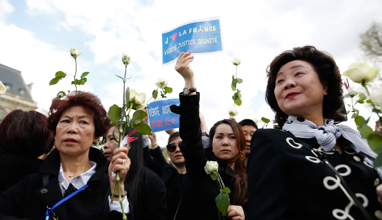 Sejumlah wanita membawa mawar putih dan spanduk saat menggelar demo di Place de la Republique, di Paris, Prancis (2/4). (AFP/Benjamin Cremel)