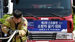 Ekspresi petugas pemadam kebakaran Lim Sung-joo saat menarik sebuah truk pemadam kebakaran dengan seutas tali dalam acara Safe Seoul Festival di Seoul, Korea Selatan, Kamis (9/5/2019). Safe Seoul Festival ditujukan bagi anak-anak dan keluarga. (AP Photo/Ahn Young-joon)