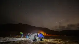 Meteor Perseid melintas di langit di atas lokasi perkemahan di gurun Negev dekat kota Mitzpe Ramon, Israel pada 11 Agustus 2020. Hujan meteor ini terjadi setiap tahun sekitar bulan Agustus, saat Bumi melayang melalui awan yang ditinggalkan oleh komet raksasa 109P / Swift-Tuttle. (MENAHEM KAHANA/AFP)